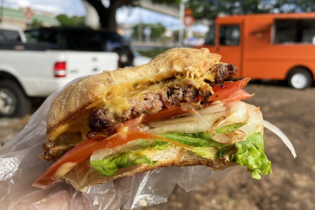 closeup of burger with colorful fresh vegetables and a huge bite taken out