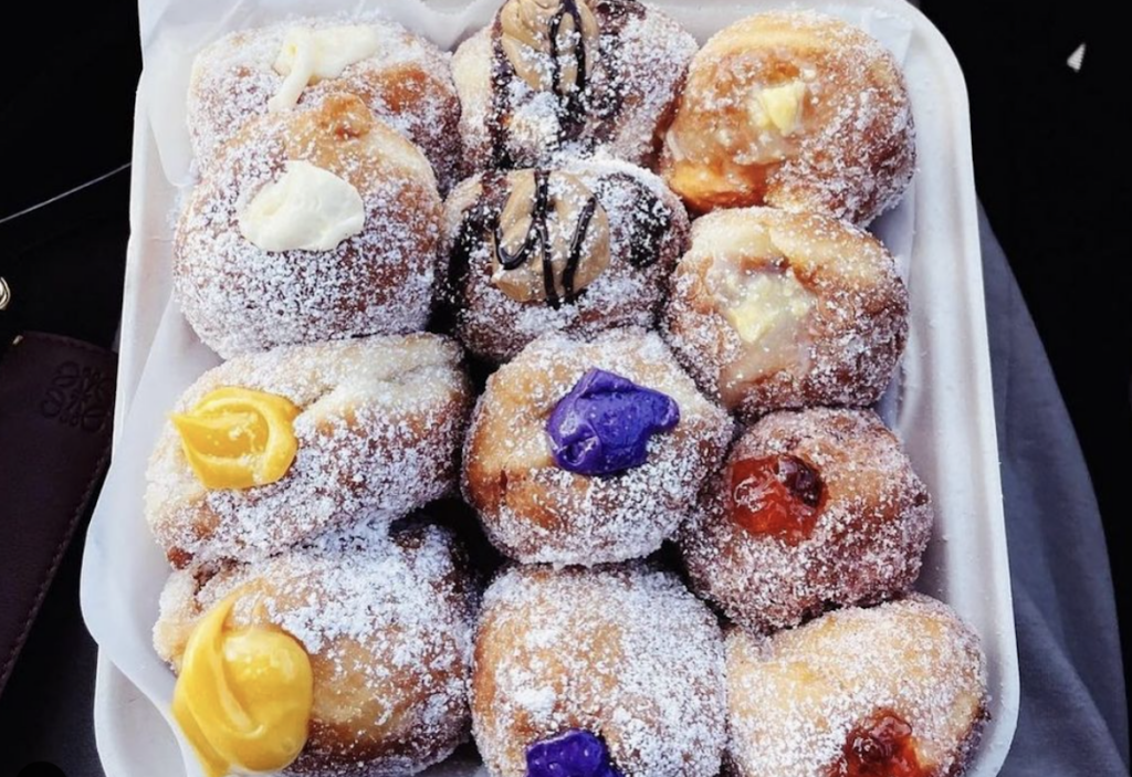 a dozen filled Malasadas in takeout clamshell